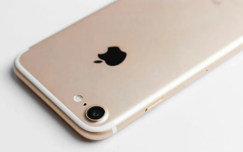 Close-up of the back of a gold iPhone showing the camera and Apple logo.