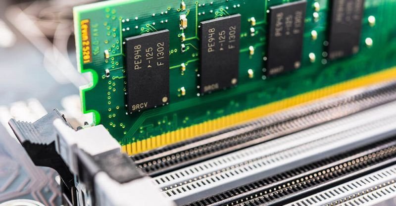 Close-up view of a computer RAM module being inserted into a motherboard slot.