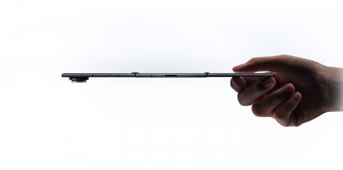 A hand holding a slim smartphone, showcasing its sleek profile against a white background.